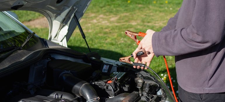 covek drzi klesta za akumulator 