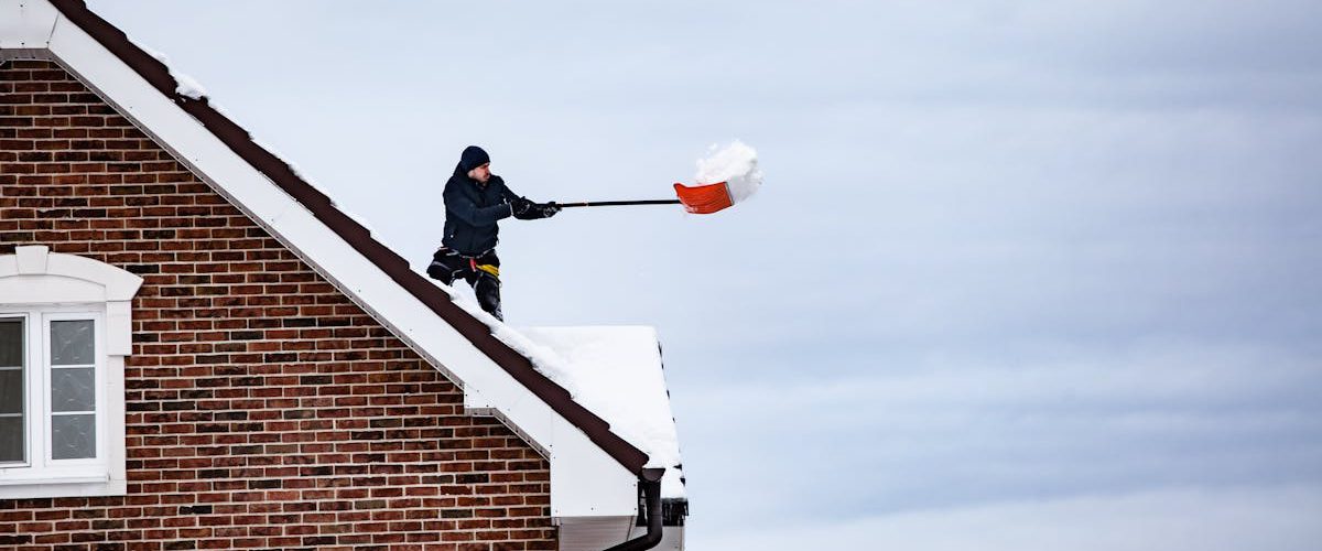 covek cisti sneg sa krova