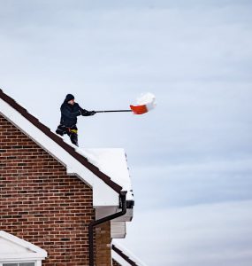 covek cisti sneg sa krova