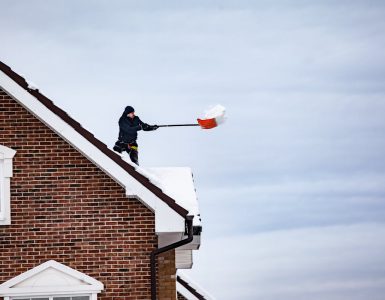covek cisti sneg sa krova