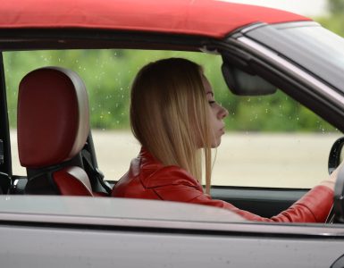 zena vozi crveno auto