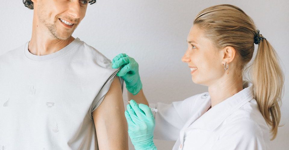 lekarka daje vakcinu protiv gripa muškarcu u nadlakticu