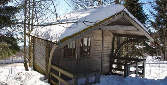 drvena vikendica prekrivena snegom u šumi