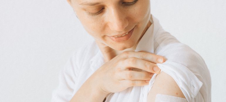 žena sa flasterom na nadlaktici nakon vakcinacije protiv gripa